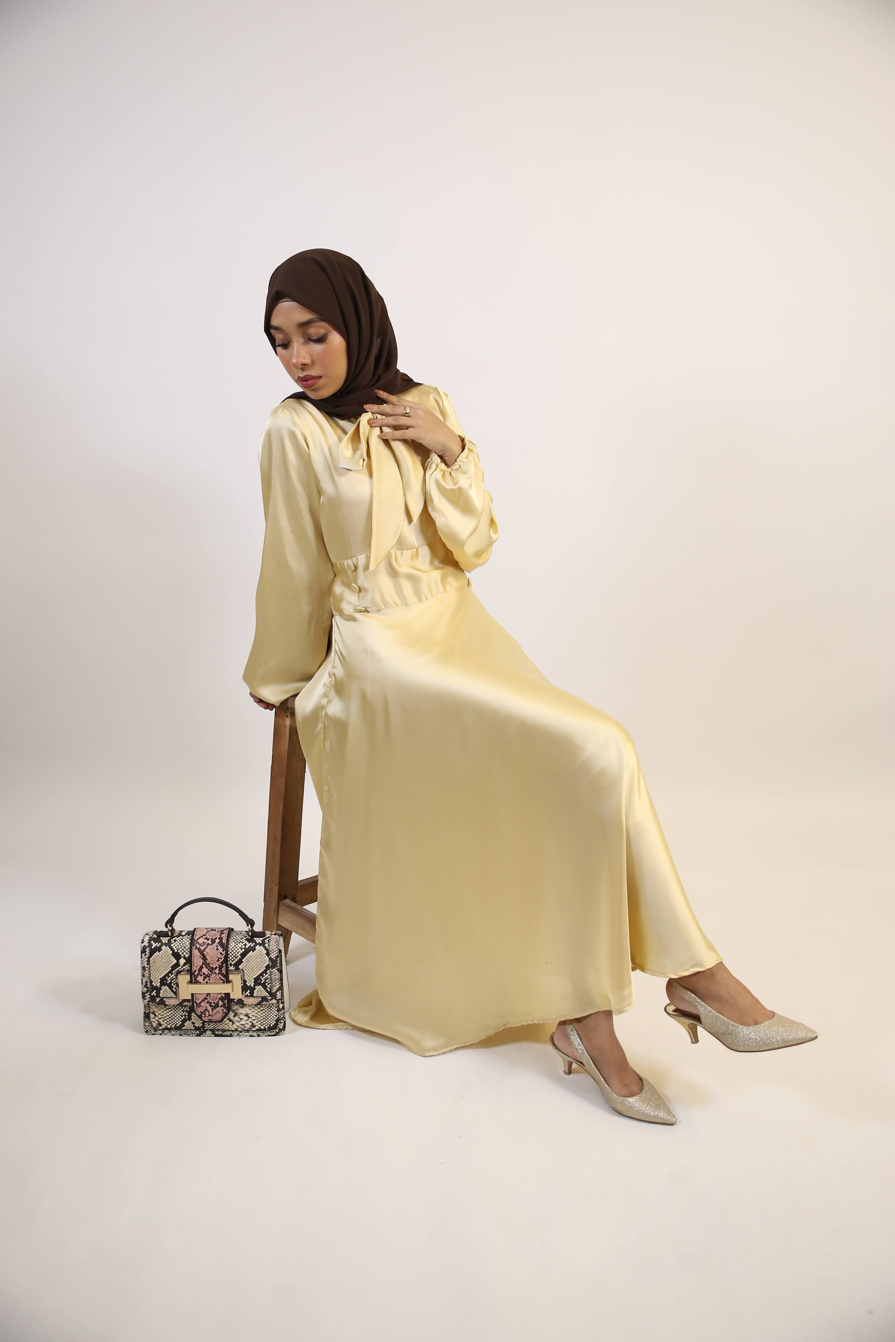 Aqeeq- Glamorous Satin Maxi dress with bow neck and waist button detailing- Pastel Yellow